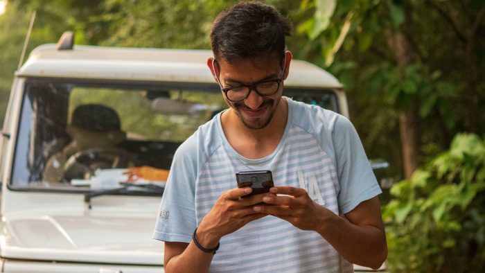 man in white crew neck t-shirt holding black smartphone